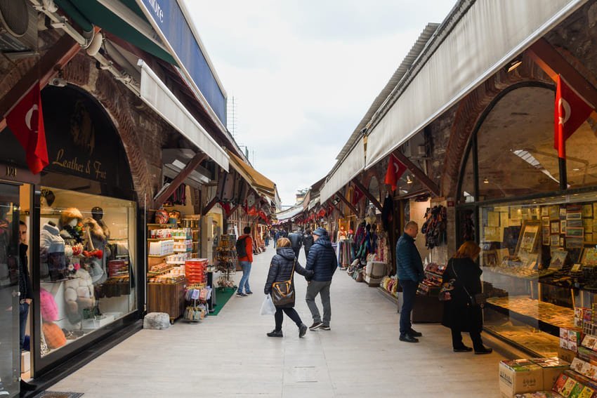 Критий ринок в Стамбулі з рядами крамниць ремесел та смаколиків, турецькі прапори й м’яке освітлення – типова торгова атмосфера.