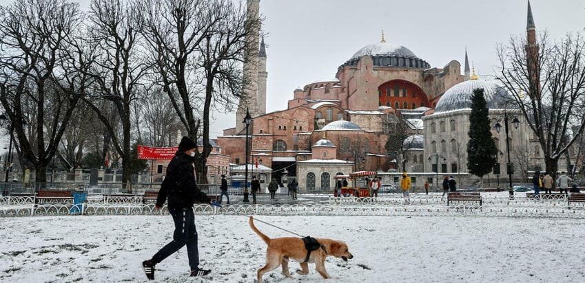 Перехожий із собакою біля Айя-Софії під снігом у зимовому Стамбулі.